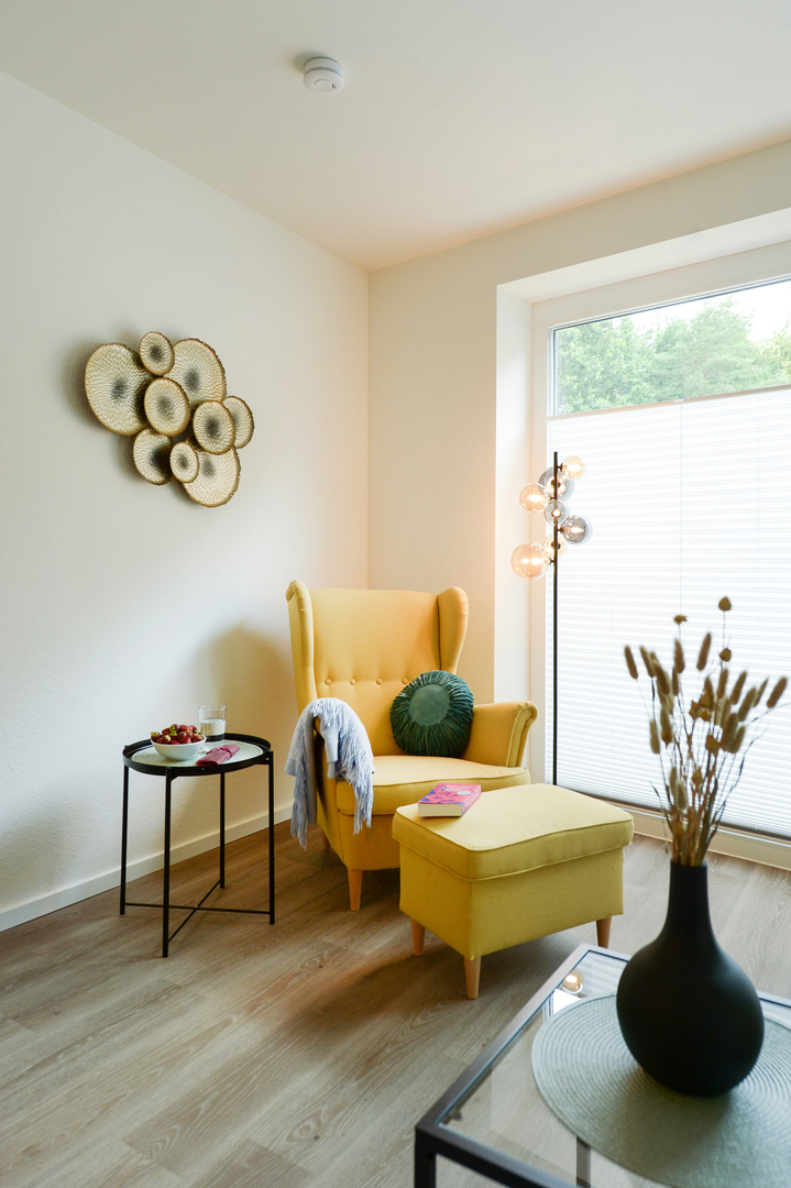 Gemütlicher Sitzbereich der Gästewohnung mit Ohrensessel, Hocker und Beistelltisch.