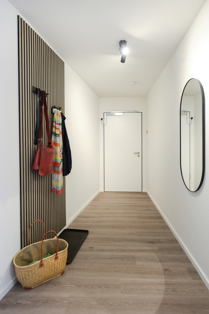 Heller Eingangsbereich der Gästewohnung mit Garderobe und großem Wandspiegel.