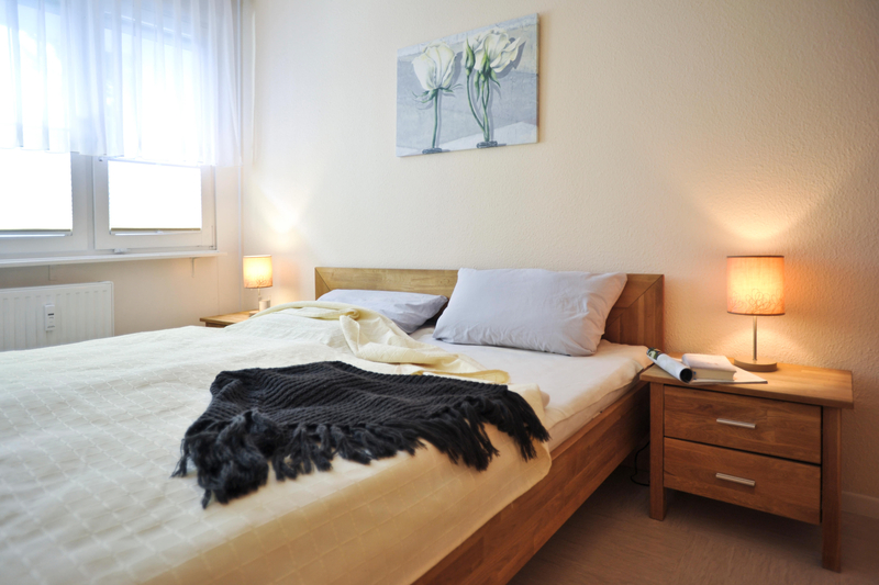Blick ins Schlafzimmer mit Doppelbett und Nachtschränken aus Holz.