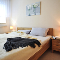 Blick ins Schlafzimmer mit Doppelbett und Nachtschränken aus Holz.