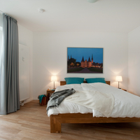 Doppelbett aus Holz, Nachttische mit Nachttischlampen.