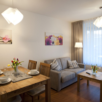 Das Wohnzimmer mit gemütlicher Couch Couchtisch aus Holz. Auch der Esstisch und die vier Stühlen sind aus Holz.
