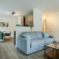 Wohnbereich der Gästewohnung Elbingstraße Heller Wohnbereich der Gästewohnung mit offener Küche, Essplatz, Schlafsofa und Blick ins Schlafzimmer.