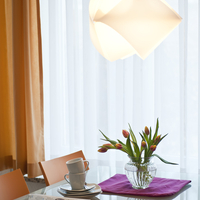 Der Esstisch wird von einer modernen Lampe beleuchtet.