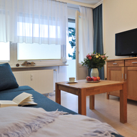 Blick vom Sofa über den Couchtisch zum Fernseher, der auf einer Kommode aus Holz steht.