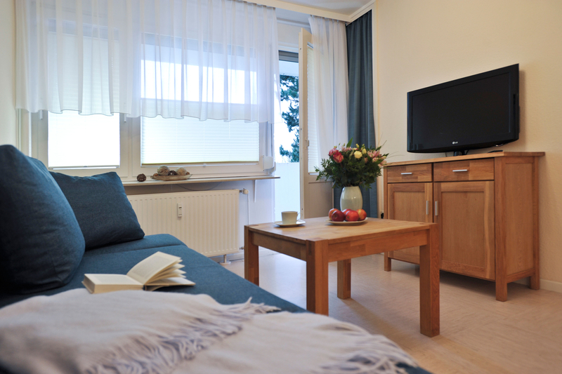 Blick vom Sofa über den Couchtisch zum Fernseher, der auf einer Kommode aus Holz steht.