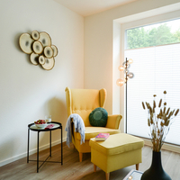 Gemütlicher Sitzbereich der Gästewohnung Gemütlicher Sitzbereich der Gästewohnung mit Ohrensessel, Hocker und Beistelltisch.