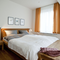 Blick in das gemütliche Schafzimmer mit Doppelbett und Nachtischen aus Holz.