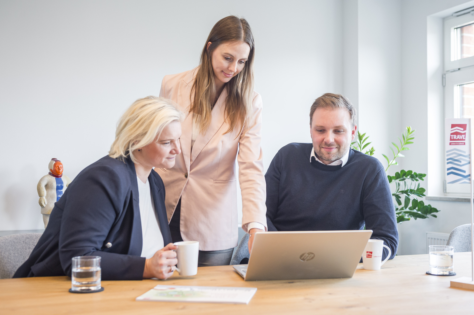 Eine Interne Besprechung. Zwei Mitarbeiterinnen und ein Mitarbeiter sehen sich etwas auf einem Laptop an.