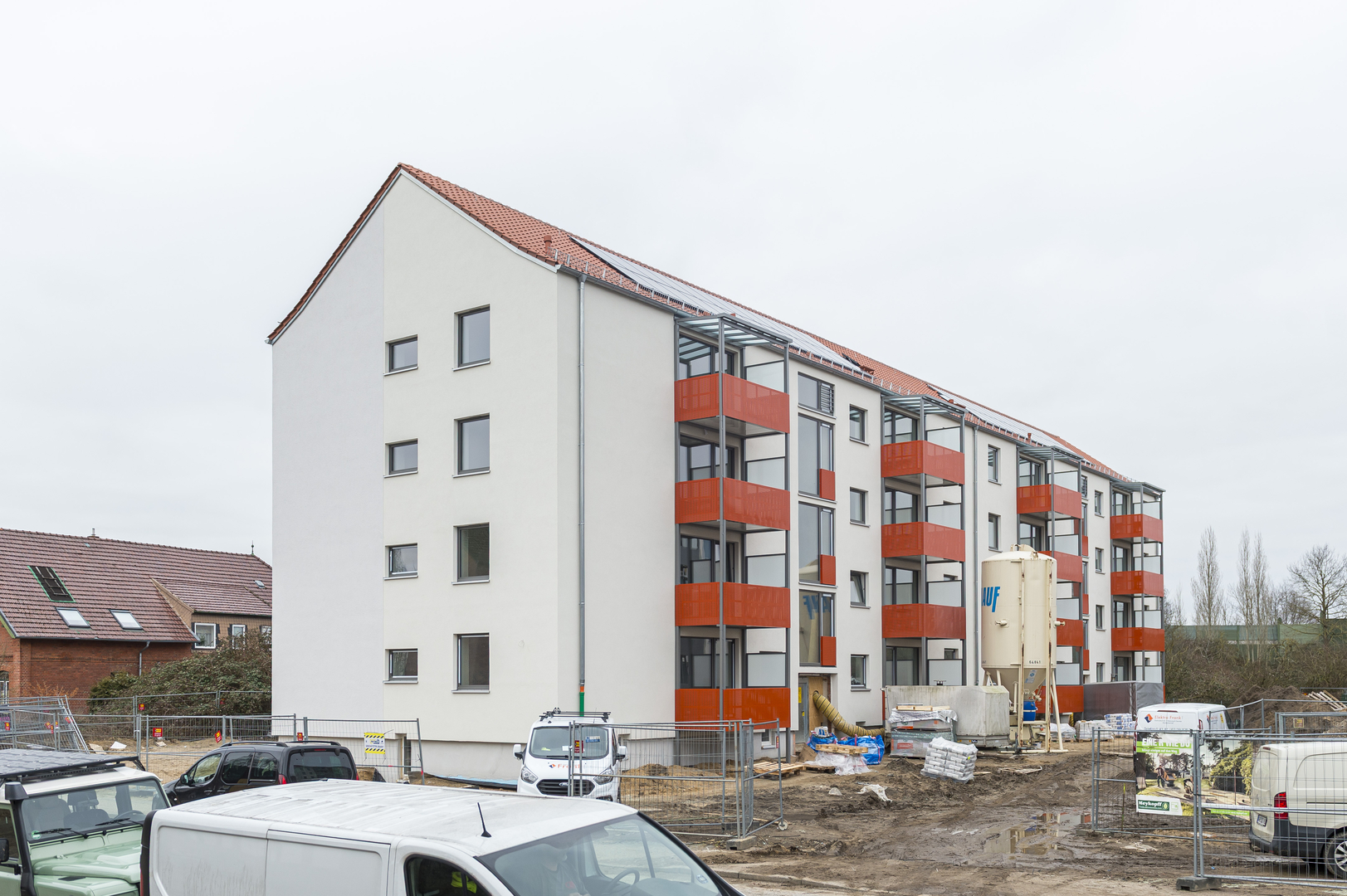 Modernisiertes Mehrfamilienhaus in der Schönböckener Straße 86/86a mit neuer Fassade und orangefarbenen Balkonen.